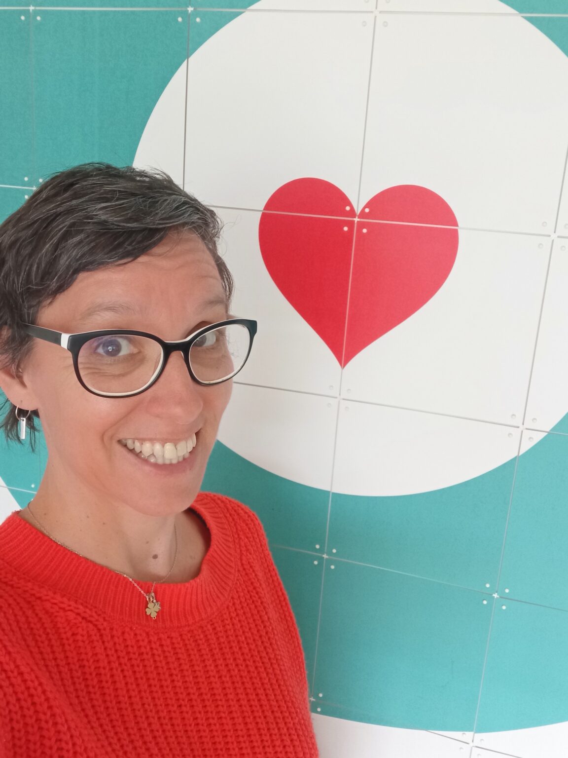 Selfie von Tanja Florin mit orangem roten Pullover und einem Herz mit Kreis