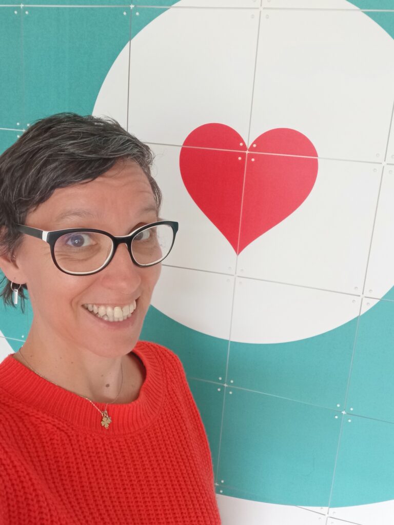Selfie von Tanja Florin mit orangem roten Pullover und einem Herz mit Kreis